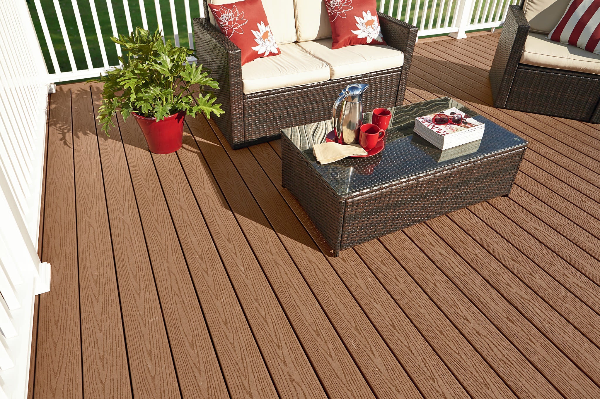 Fiberon composite decking with wicker furniture, red and white pillows, and a tray with cups enhances outdoor spaces.