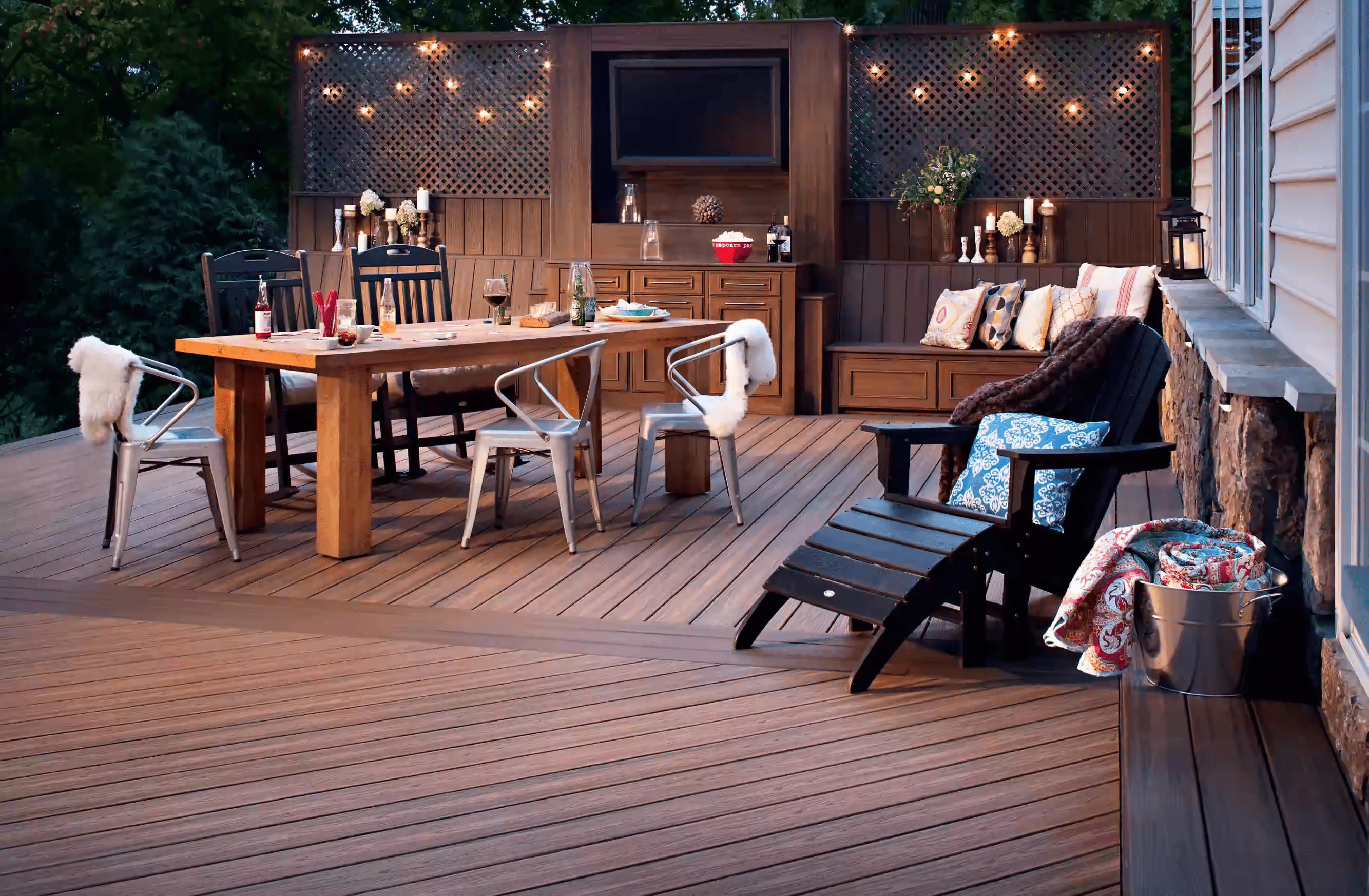 Image of brown dining table on brown deck with hanging lights.